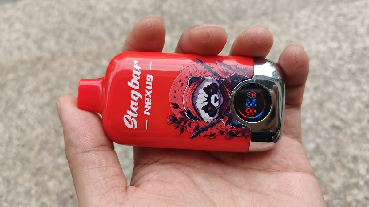 A detailed close-up photograph of a hand presenting the red Stagbar Nexus disposable vape device